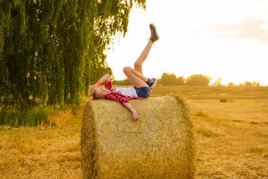 Bir alandaki saman sheaves genç kız