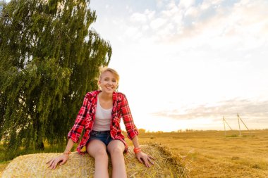 Bir alandaki saman sheaves genç kız