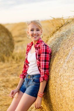 Bir alandaki saman sheaves genç kız