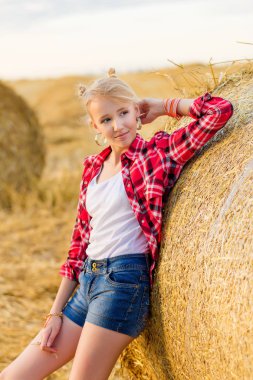 Bir alandaki saman sheaves genç kız