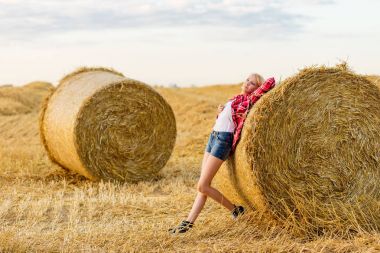 Bir alandaki saman sheaves genç kız
