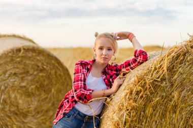 Bir alandaki saman sheaves genç kız