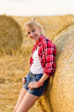 Bir alandaki saman sheaves genç kız