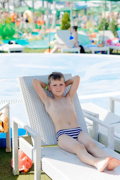 Kleiner Junge im Badeanzug auf einem Regal am Pool — Stockfoto