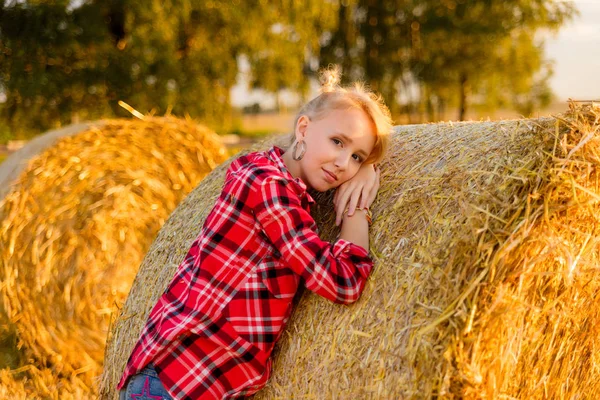 Junges Mädchen auf Strohgarben auf einem Feld — Stockfoto