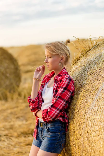 Ung flicka på halm kärvar i ett fält — Stockfoto