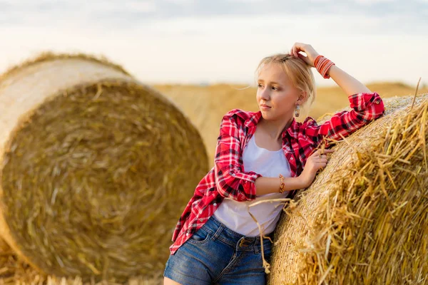 Bir alandaki saman sheaves genç kız