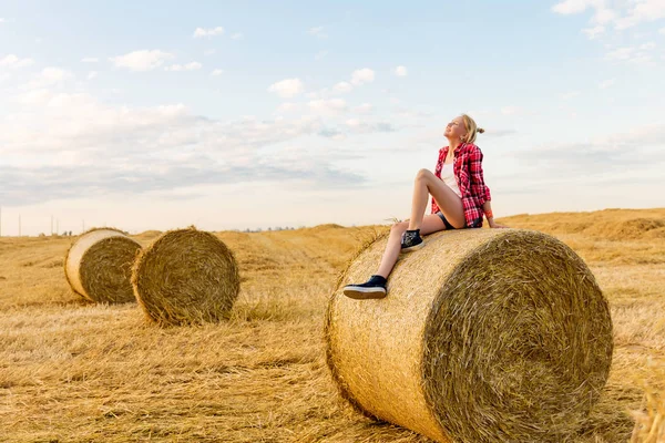Bir alandaki saman sheaves genç kız