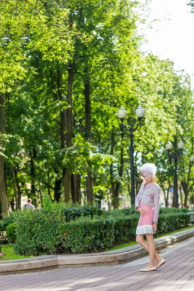 Açık havada bir parkta pembe elbiseli genç bir sarışın portresi.