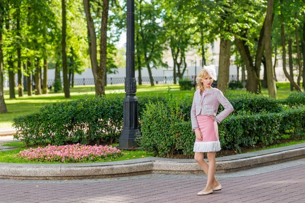 Portrait d'une jeune blonde en costume rose dans un parc à l'extérieur . — Photo