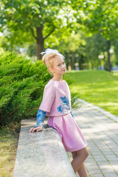 Portret van een blond in roze kleding in een park buiten. — Stockfoto