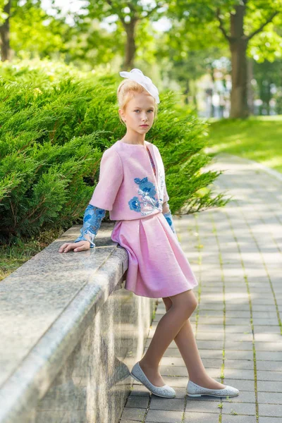 Portret van een blond in roze kleding in een park buiten. — Stockfoto