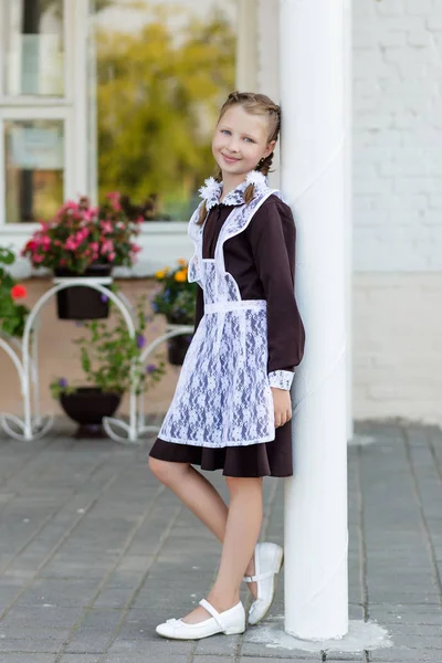 Retrato de uma menina bonita em um uniforme escolar antes da aula em — Fotografia de Stock