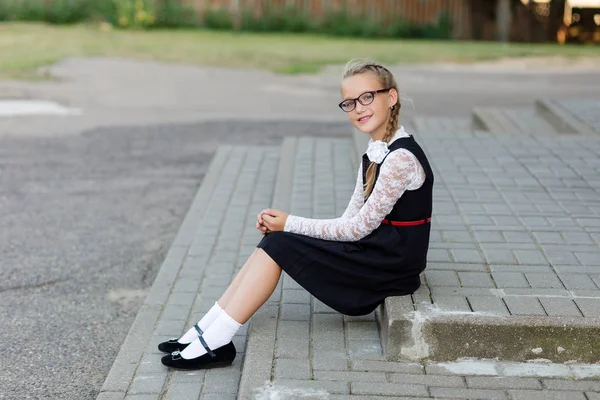 Mladá školačka s brýlemi a školní uniformu venku v fro — Stock fotografie