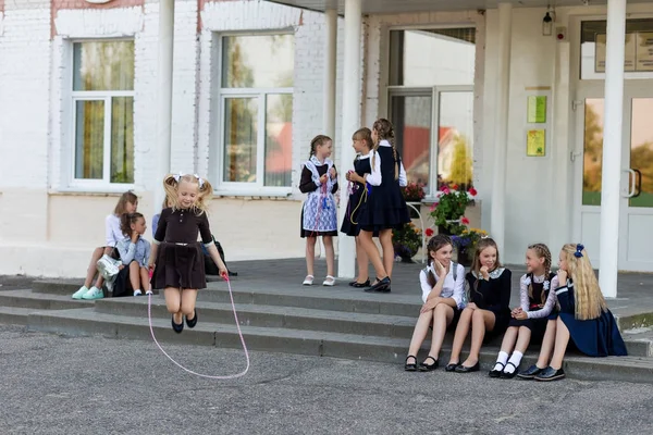 Skolepiger hopper på et reb til en forandring foran skolen - Stock-foto