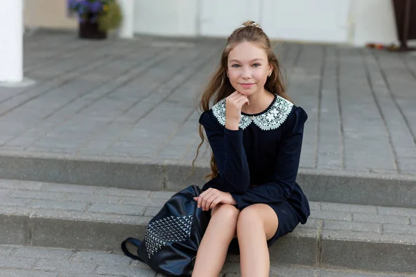 Красивая школьница в школьной форме с рюкзаком на диване — стоковое фото