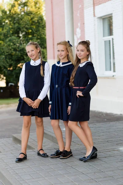 Alunas em uniforme escolar descansam em uma pausa perto da escola — Fotografia de Stock