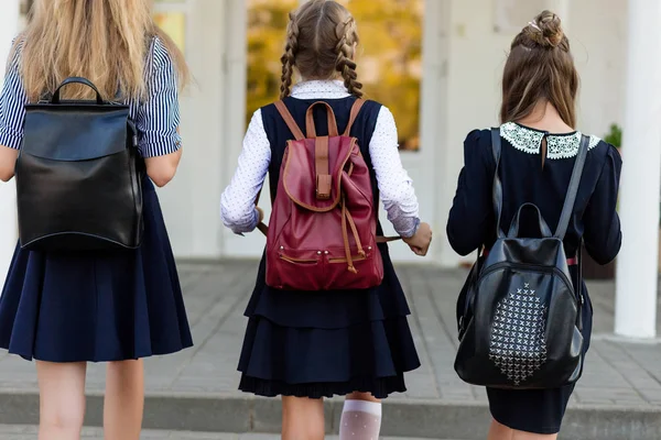 Tres niñas en uniforme escolar con mochilas de pie en las escaleras —  Fotos de Stock