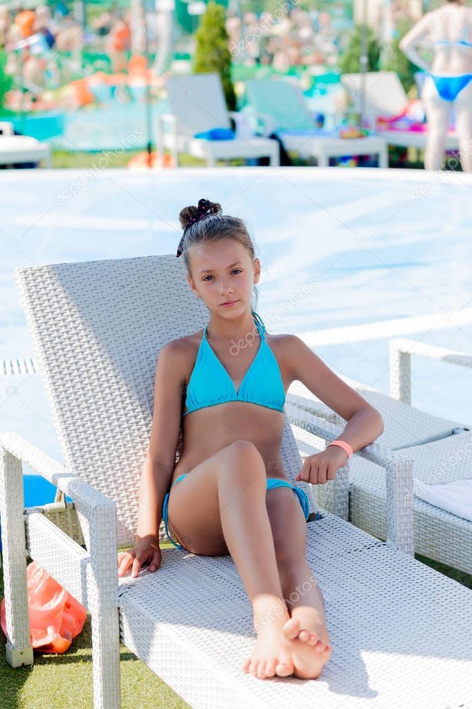 Young girl in a swimsuit on a shelf by the pool