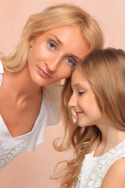 Mom with her daughter in white dresses in the studio. — Stockfoto