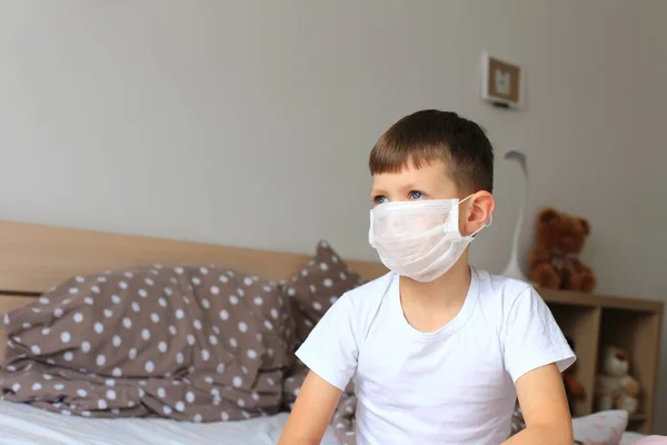 A boy in a respiratory mask sits in quarantine at home — Stock Photo, Image