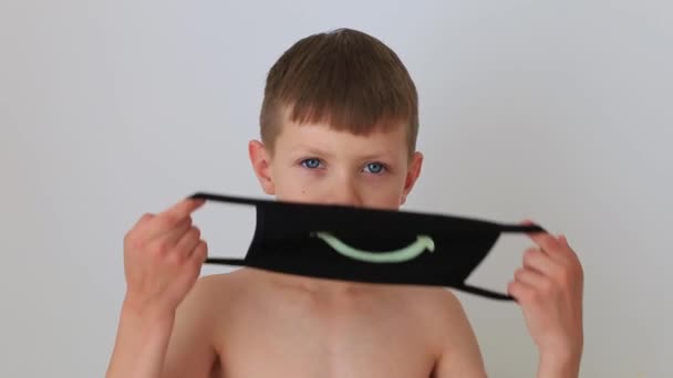 Хлопчик одягає карантинну респіраторну маску вдома — стокове відео