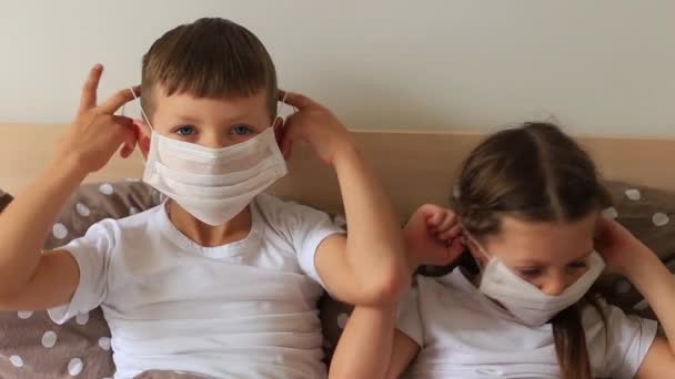 Niños en una máscara respiratoria se sienta en cuarentena en casa — Vídeos de Stock