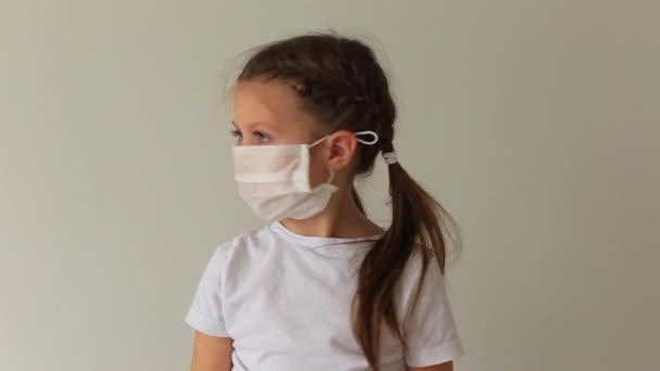 Chica en una máscara respiratoria se sienta en cuarentena en casa . — Vídeo de stock