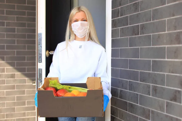 Μια γυναίκα στέκεται στην πόρτα με ένα κουτί γεμάτο φρούτα και λαχανικά.. — Φωτογραφία Αρχείου