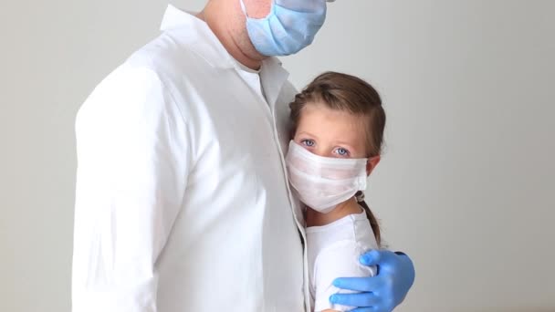 Il dottore abbraccia una bambina con una maschera respiratoria . — Video Stock