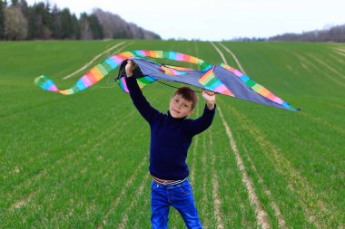 Çocuk baharda bir tarlaya uçurtma fırlatıyor..