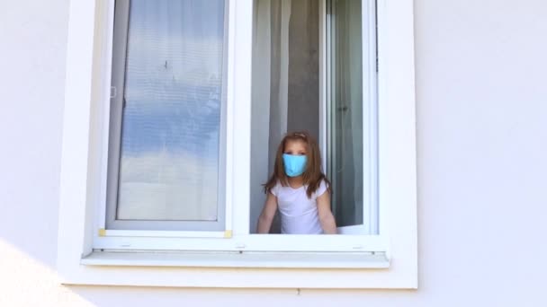 Kleines Mädchen blickt aus dem offenen Fenster in die Isolation. — Stockvideo