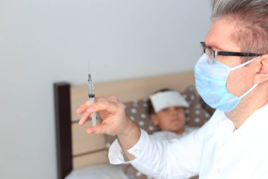 Doktor hasta bir çocuğa iğne yapacak.