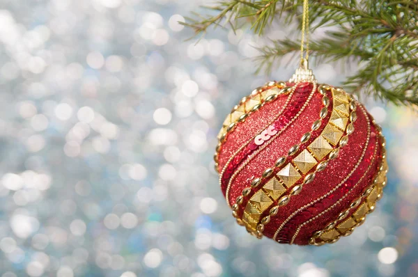 Boule de Noël rouge sur une branche d'arbre de Noël sur fond luisant flou, gros plan . — Photo