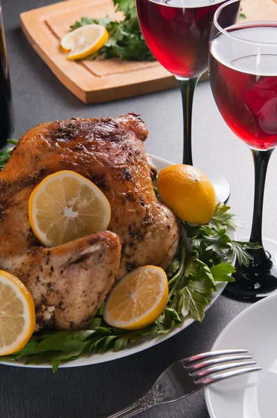 Garnished roasted turkey on holiday decorated table with glasses of red wine Stock Picture