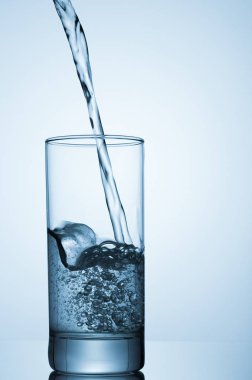 üzerinde mavi arka plan cam içine dökülen su