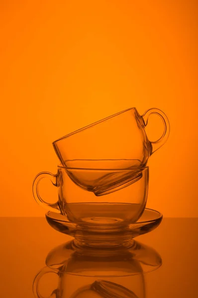 Zwei transparente Glasbecher orange Hintergrund — Stockfoto