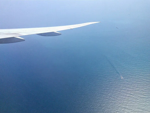 Aviones ala sobre el mar tranquilo con agua quieta y barcos de sellado. Volando sobre el mar azul limpio. Anuncio de la compañía aérea para viajar en países exóticos con clima cálido . —  Fotos de Stock