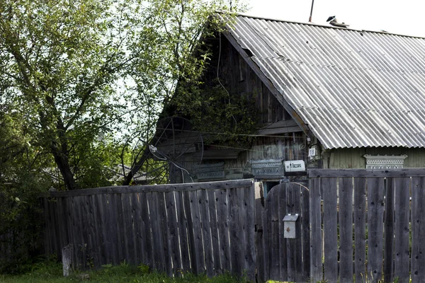 Falusi gazdaság fából készült ház és a fából készült kerítés és a fa. Szegény ház szegény ember. Etnikai Faluház — Stock Fotó