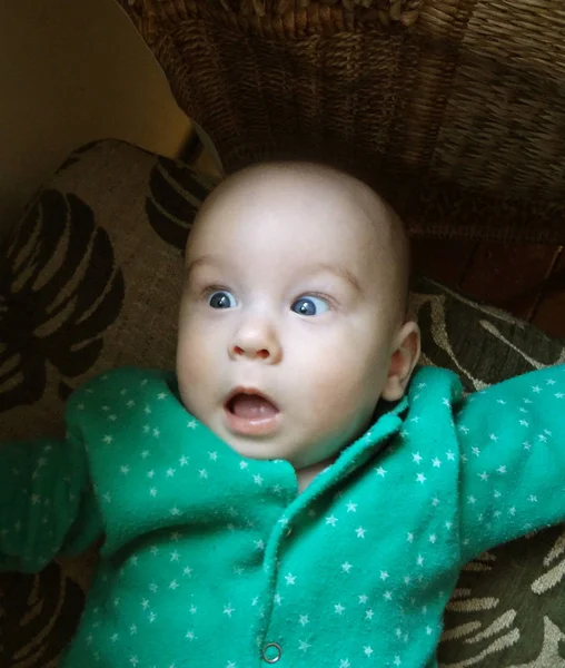 Open-eyed en verbaasd baby jongetje in groene kleden. Verbazingwekkende en blij gezicht — Stockfoto