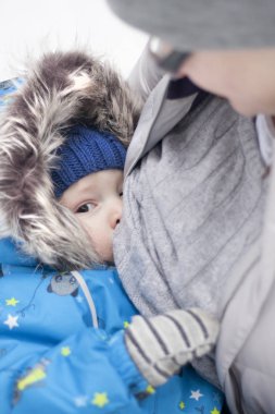 Olağandışı durumda anne sütüyle. Anne Bebek dışında soğuk kış havada besleme. Hava, mutlu ve sakin rağmen çocuk emzirir.