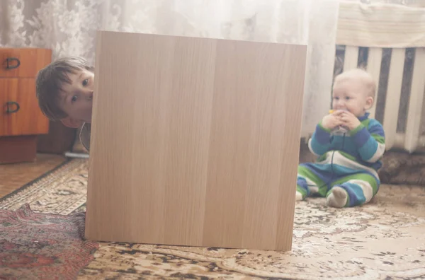 Kleine jongen verstopt achter houten meubilair — Stockfoto
