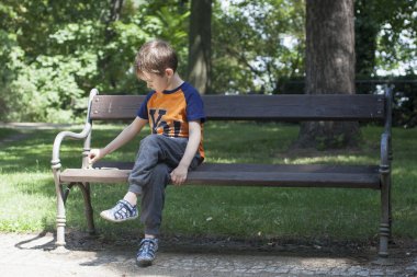 Çocuk sakin ol bankta yeşil park.