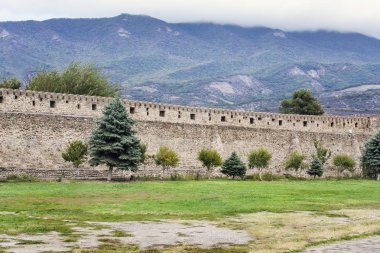 Anne ve kızı büyük antik duvar altında yürümek