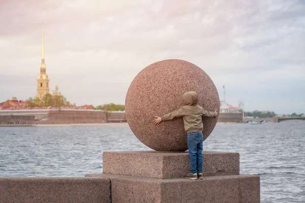 Chłopak próbuje przytulić ogromny kamień piłkę w Sankt Petersburg. Zdjęcia Stockowe bez tantiem