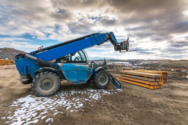 İnşaat alanında forklift, inşaat parçalarını kaldırmaya hazırlanıyor.