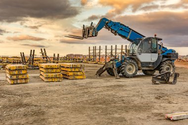 İnşaat alanında forklift, inşaat parçalarını kaldırmaya hazırlanıyor.