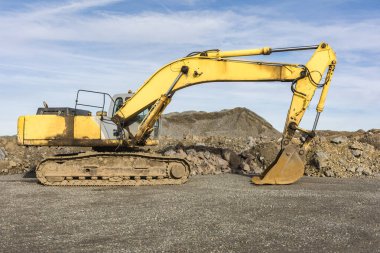 Taş ocağında hareket eden büyük sarı bir kazıcı.