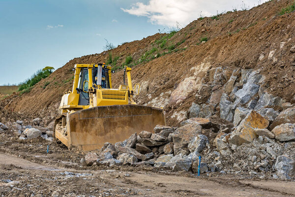 Excavator moving granite and other rocks in the construction of a road