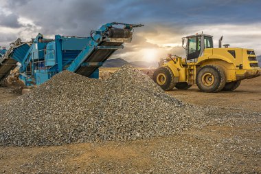 Kazıcı açık bir madende taş topluyor.